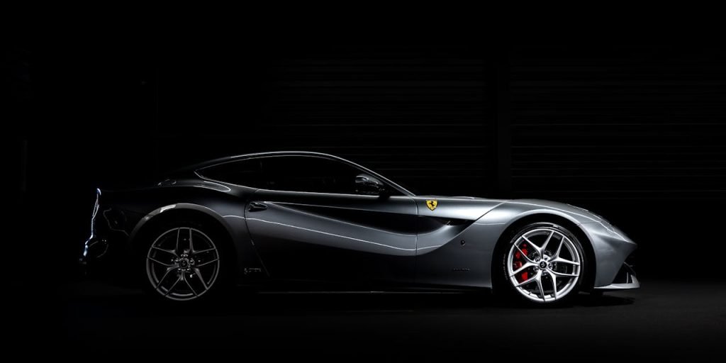 Side profile of a luxury sports car against a dark background, showcasing sleek design.
